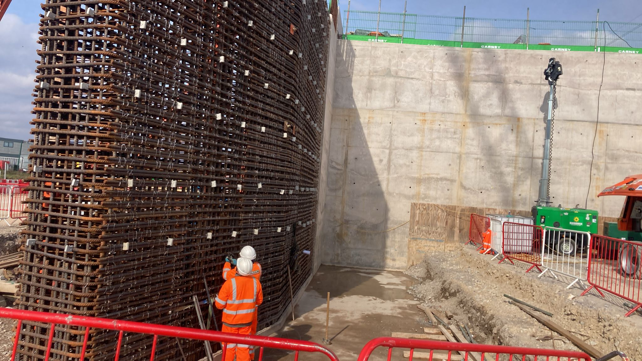 Rebar cage next to finished concrete wall